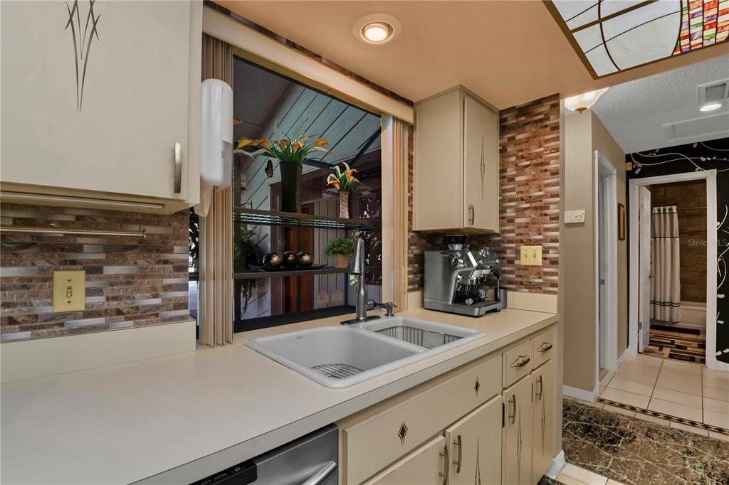 A kitchen features a double-basin sink, beige cabinets, a tiled backsplash, and a window view — 3884 VILLA ROSE LANE, ORLANDO, FL