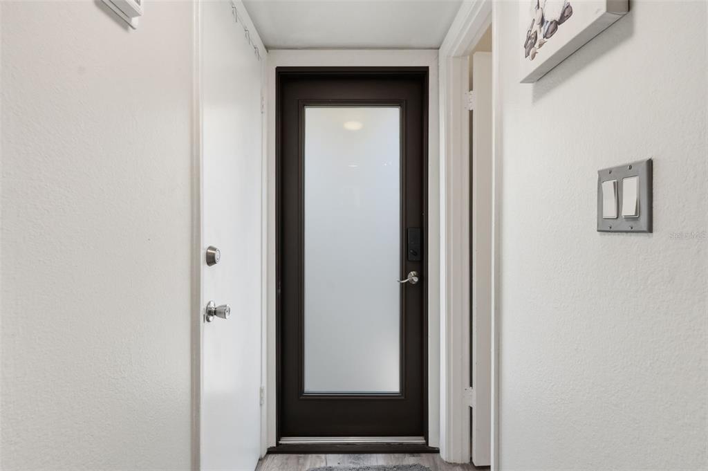 A hallway features a dark brown door with a frosted glass panel and white walls — 501 E BAY DRIVE UNIT 202, LARGO, FL