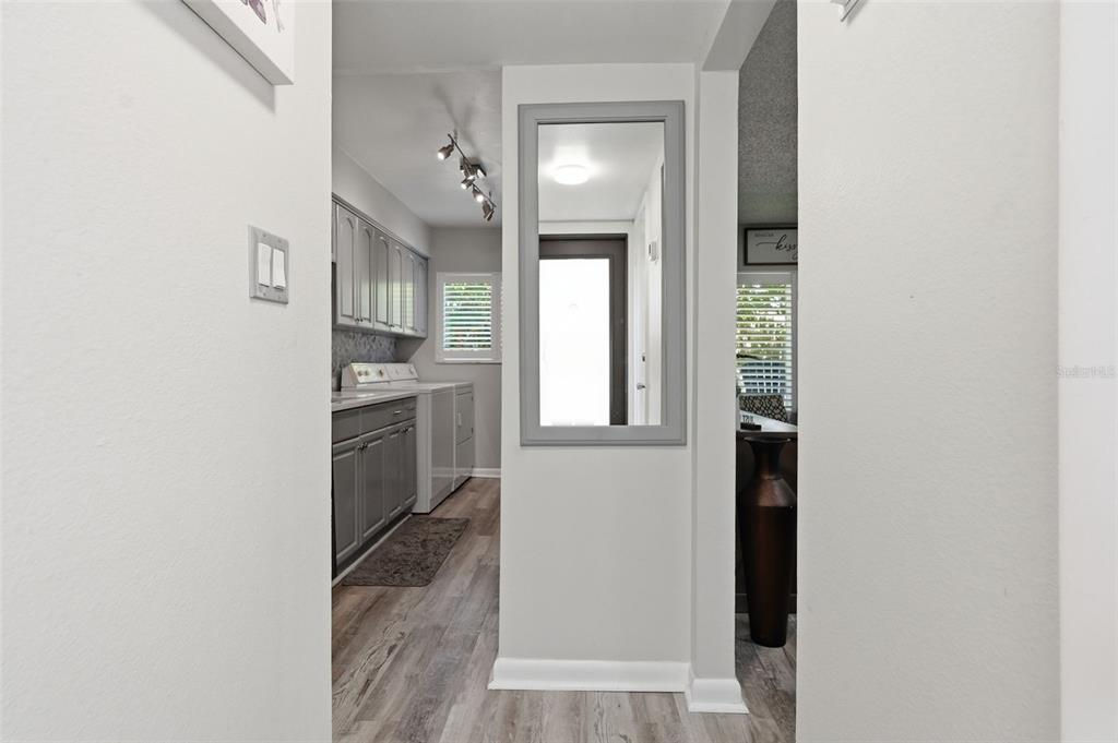 A hallway leads to a laundry room with gray cabinets and wood-look flooring — 501 E BAY DRIVE UNIT 202, LARGO, FL