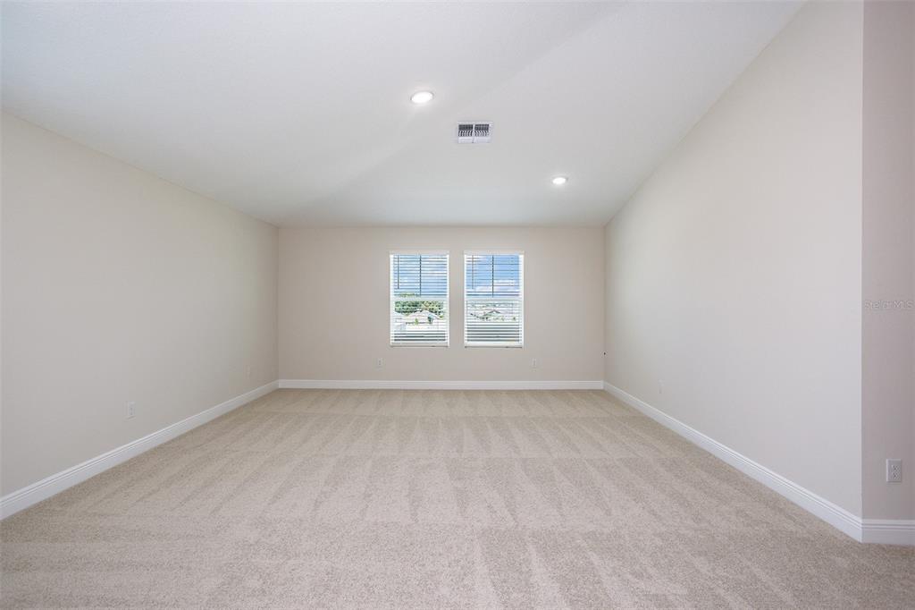 An empty room with beige walls, light-colored carpeting, and two windows with white blinds — 9886 ANNUNCIATION DRIVE, WESLEY CHAPEL, FL