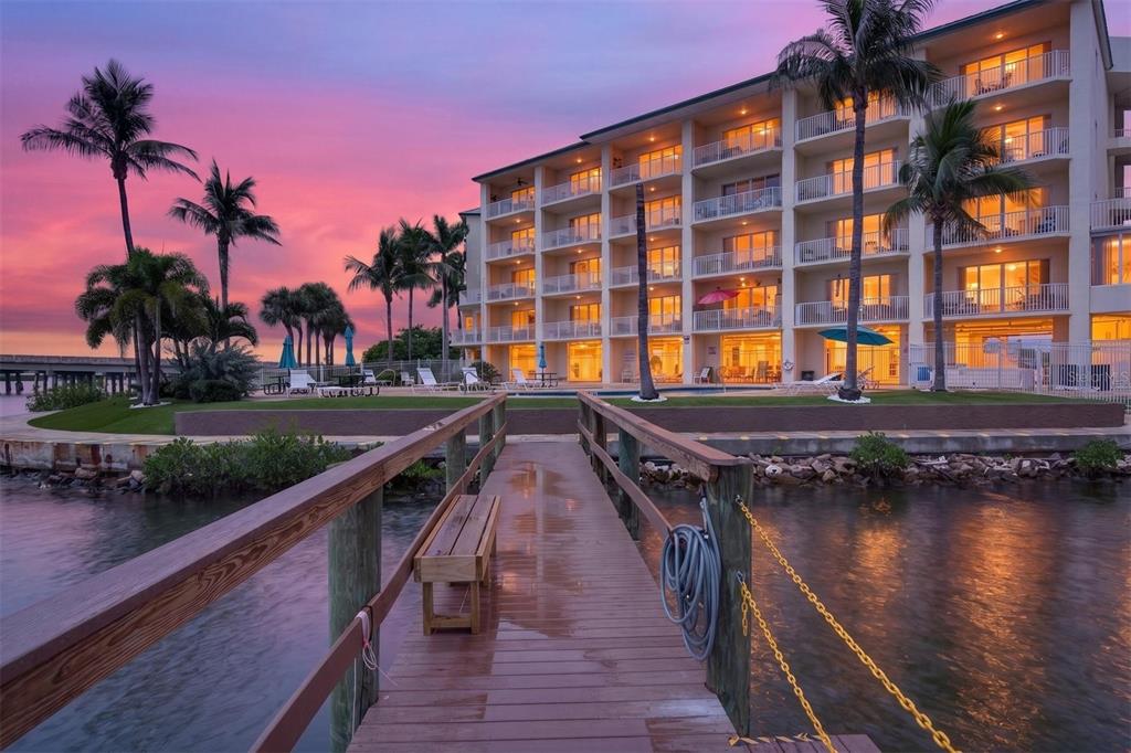 A multi-story apartment building with a large parking lot and palm trees in front — 8800 BAY PINES BOULEVARD UNIT 216, ST PETERSBURG, FL