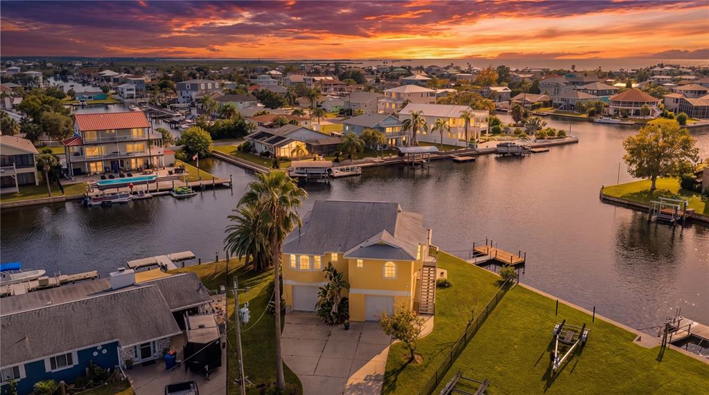An aerial view shows a yellow waterfront house on a corner lot with two docks — 4365 4TH ISLE DRIVE, HERNANDO BEACH, FL