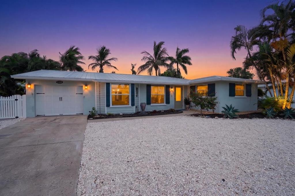 A single-story house with a white garage, light blue siding, and a gravel front yard — 520 69TH STREET, HOLMES BEACH, FL