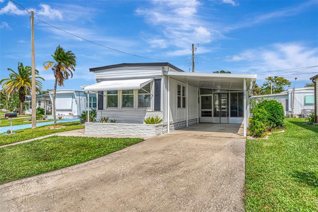 A white mobile home with a carport and a small front patio under a blue sky — 259 INNER DRIVE E, VENICE, FL