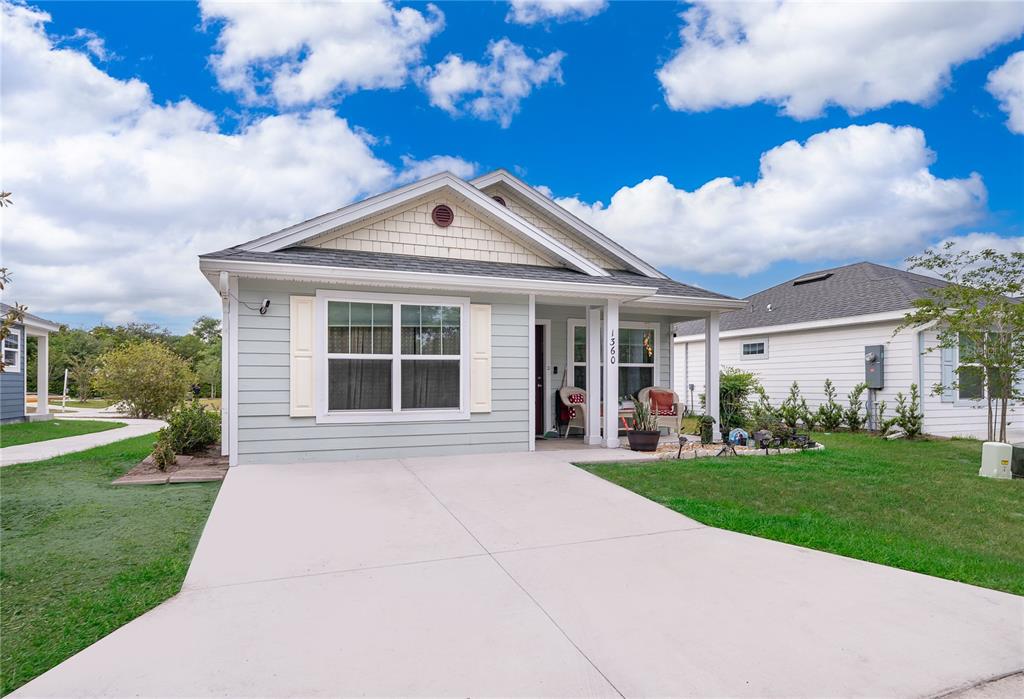 A light blue single-story house with a concrete driveway and a covered front porch — 1360 COTTAGE CIRCLE, TAVARES, FL