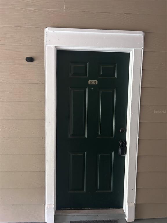 A dark green front door with the number 1031 is set in a tan-sided wall — 13015 PLANTATION PARK CIRCLE UNIT 1031, ORLANDO, FL