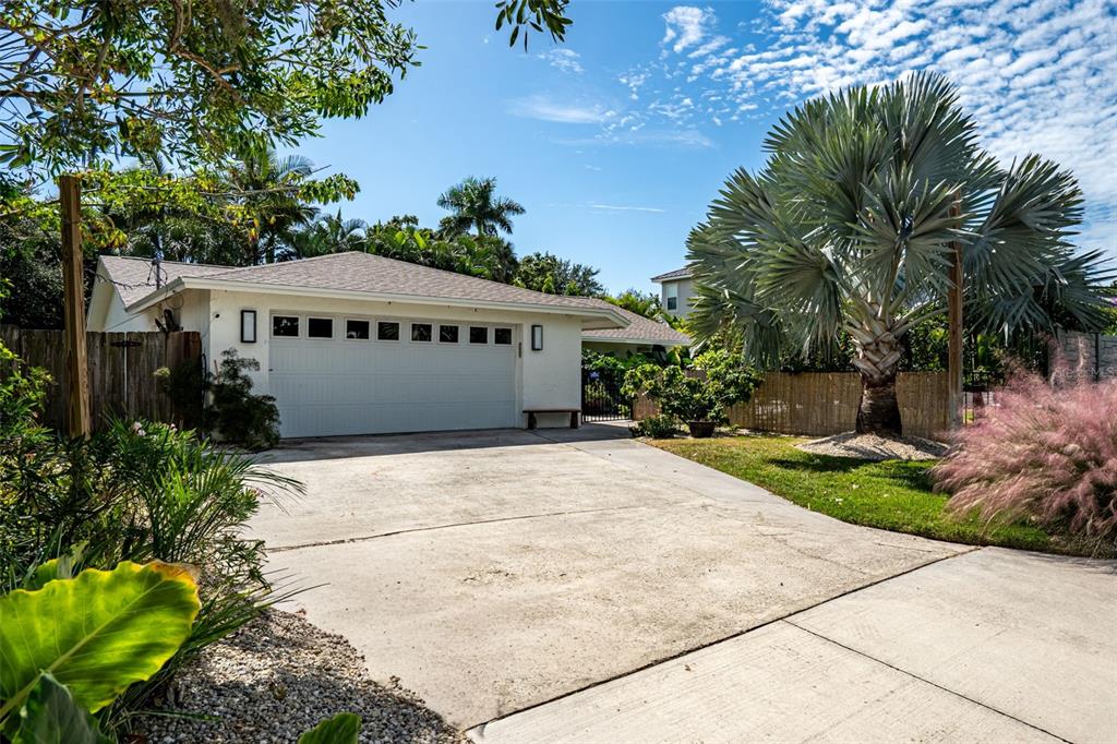 A concrete driveway leads to a single-story house with a two-car garage and palm trees — 1750 ALTA VISTA STREET, SARASOTA, FL
