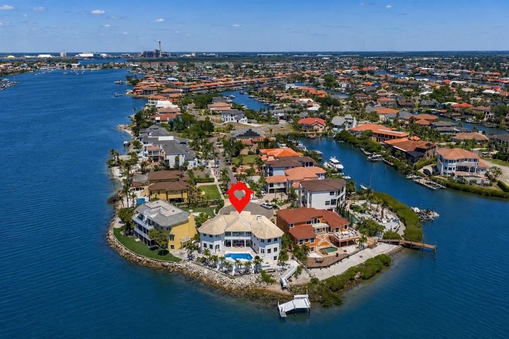 An aerial view shows a large waterfront house with a pool on a peninsula — 1021 SYMPHONY ISLES BOULEVARD, APOLLO BEACH, FL