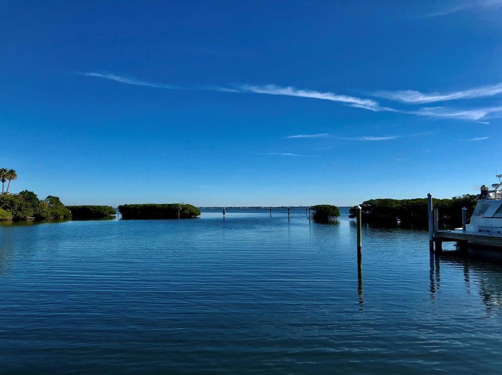 A view of a calm bay with mangroves, wooden pilings, and a boat dock — 2600 HARBOURSIDE DRIVE UNIT C-04, LONGBOAT KEY, FL