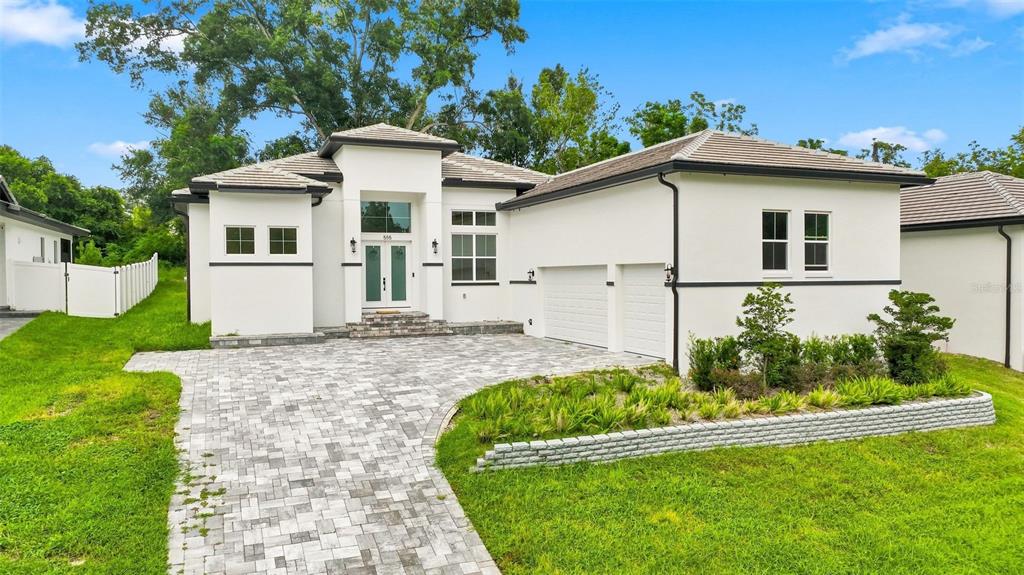 A modern white house with a paver driveway, two-car garage, and a landscaped front yard — 555 SANCTUARY GOLF PLACE, APOPKA, FL