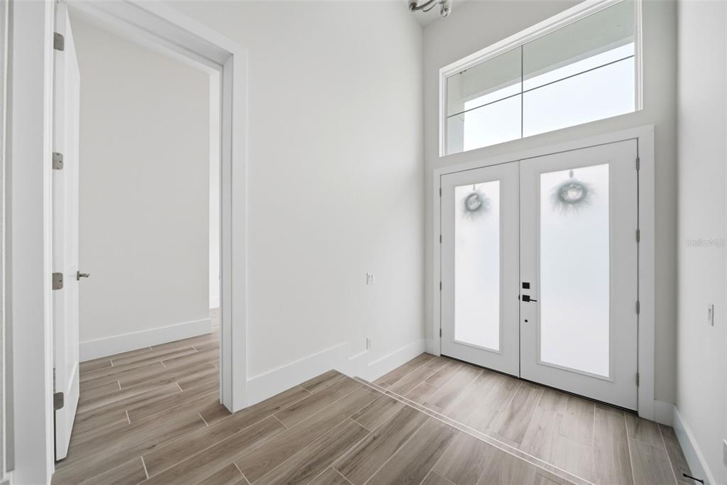 An entryway with wood-look tile flooring, white walls, and double front doors with frosted glass — 555 SANCTUARY GOLF PLACE, APOPKA, FL