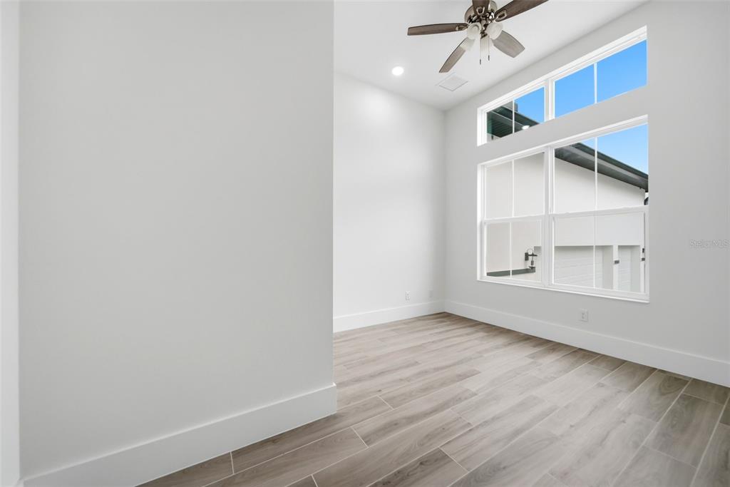A bright room features light wood-look tile flooring, white walls, and a ceiling fan — 555 SANCTUARY GOLF PLACE, APOPKA, FL