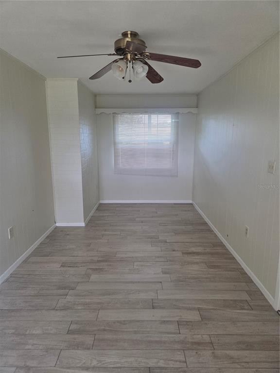 An empty living room features light wood-look flooring, a white brick fireplace, and black curtains — 5903 RIVIERA DRIVE, ORLANDO, FL