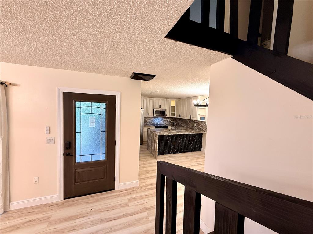 An entryway with a dark wood door leads to a kitchen featuring a marble island — 2747 5TH CT, PALM HARBOR, FL
