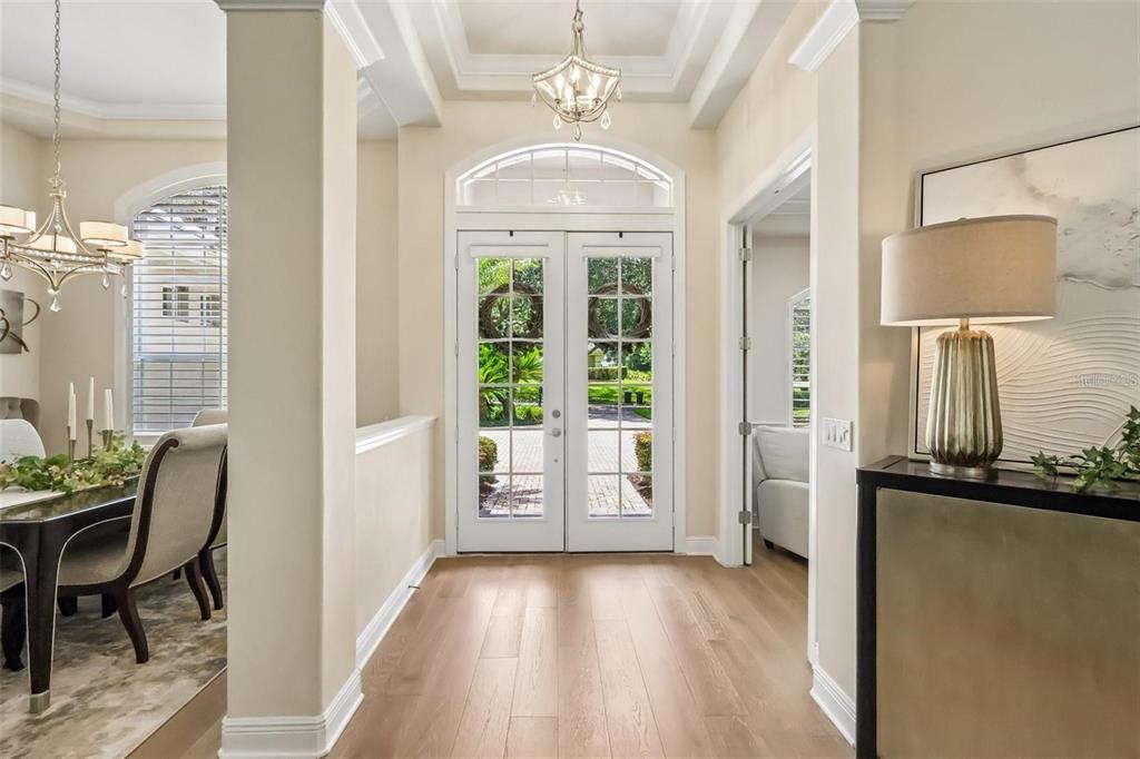 A bright foyer features light wood flooring, double glass entry doors, and a decorative chandelier — 3274 OAKMONT TERRACE, LONGWOOD, FL