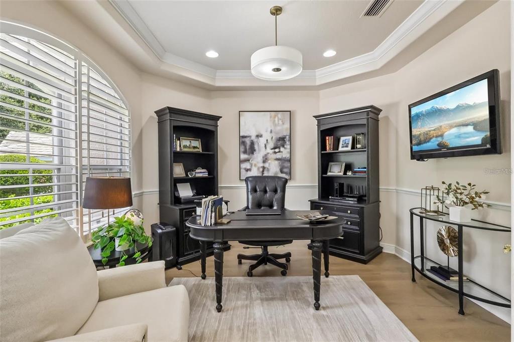 A home office features a dark wood desk, matching bookshelves, a leather chair, and a television — 3274 OAKMONT TERRACE, LONGWOOD, FL