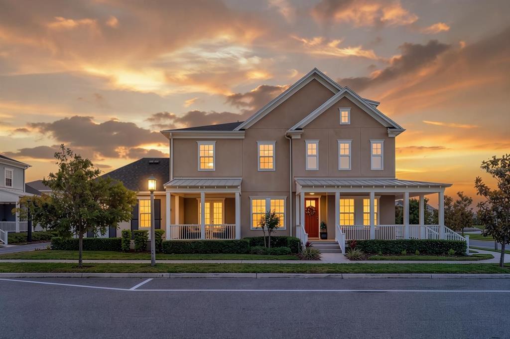 A two-story tan house with a covered front porch and a red front door — 1851 COASTAL COURT, CELEBRATION, FL