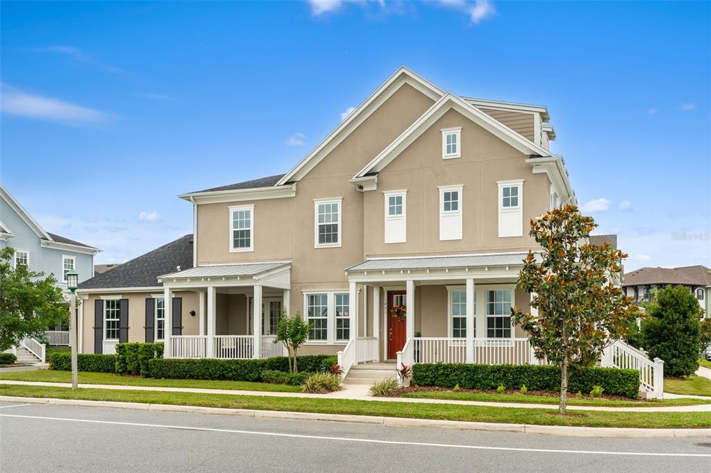 A two-story house with a wrap-around porch and a red front door at sunset — 1851 COASTAL COURT, CELEBRATION, FL