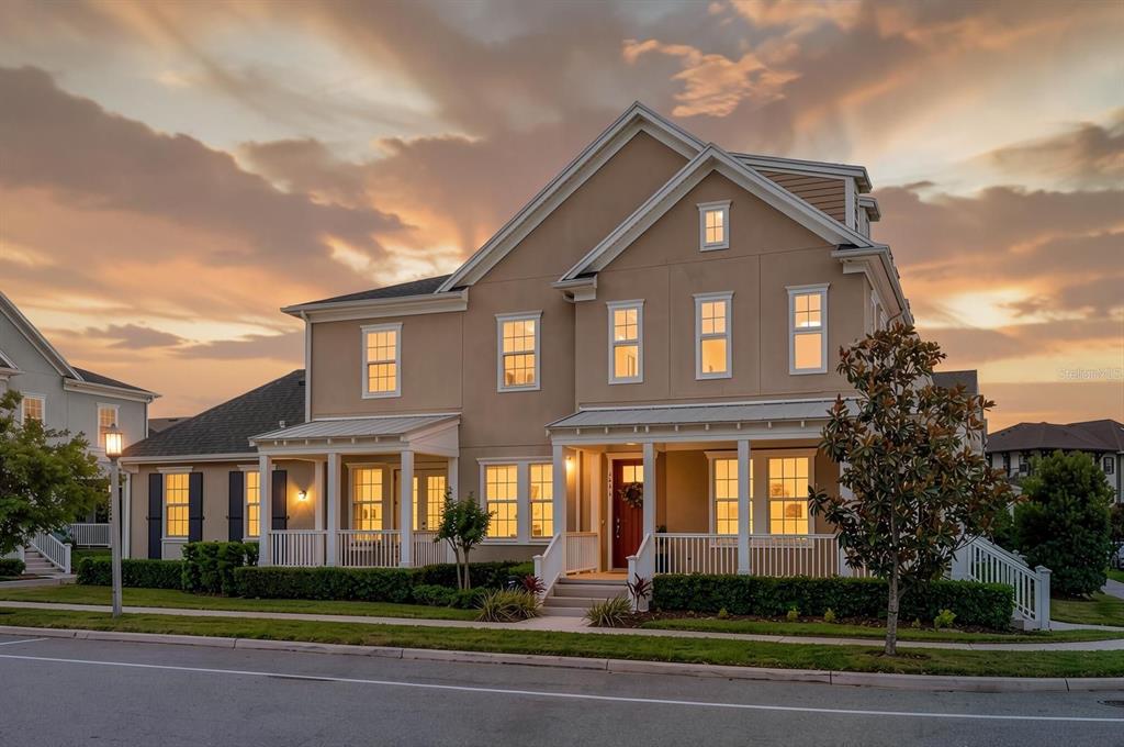 A two-story beige house with a wrap-around front porch and a red front door — 1851 COASTAL COURT, CELEBRATION, FL