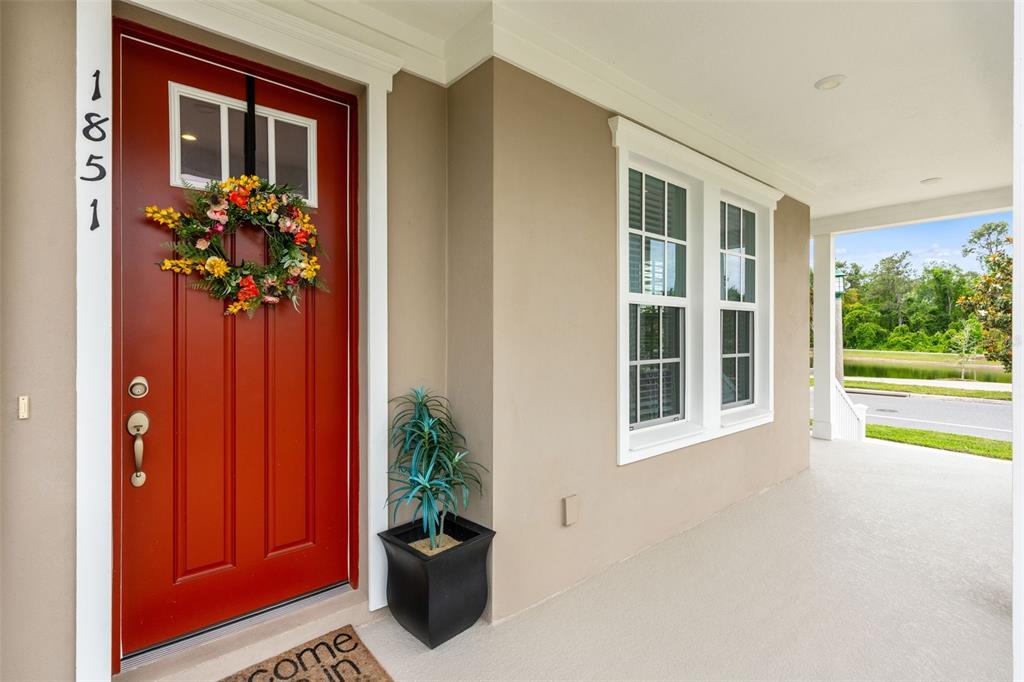 A red front door with a wreath and house numbers sits on a covered porch — 1851 COASTAL COURT, CELEBRATION, FL
