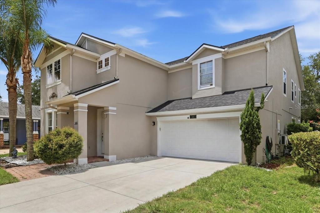 A two-story house with a beige stucco exterior, a two-car garage, and a concrete driveway — 4415 BLUE MAJOR DRIVE, WINDERMERE, FL