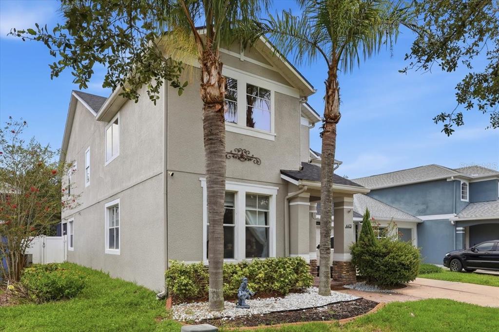 A two-story house with a beige stucco exterior, two palm trees, and a front porch — 4415 BLUE MAJOR DRIVE, WINDERMERE, FL