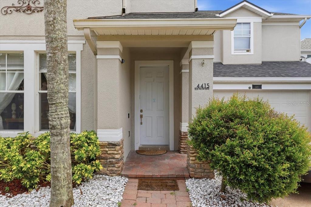 The exterior of a house features a white front door, stone accents, and landscaping — 4415 BLUE MAJOR DRIVE, WINDERMERE, FL