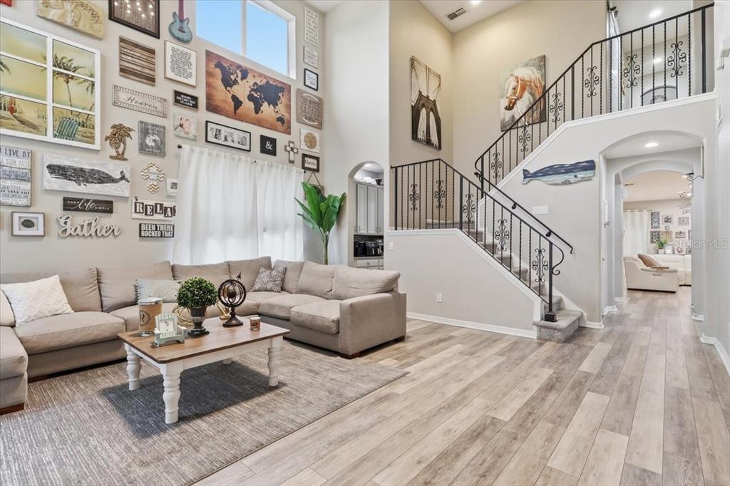 A living room features a high ceiling, a large gallery wall, and a staircase — 4415 BLUE MAJOR DRIVE, WINDERMERE, FL