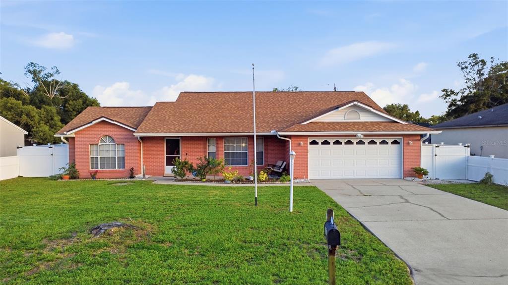 A single-story brick house features a two-car garage, a front lawn, and a concrete driveway — 2287 BELEN DRIVE, DELTONA, FL