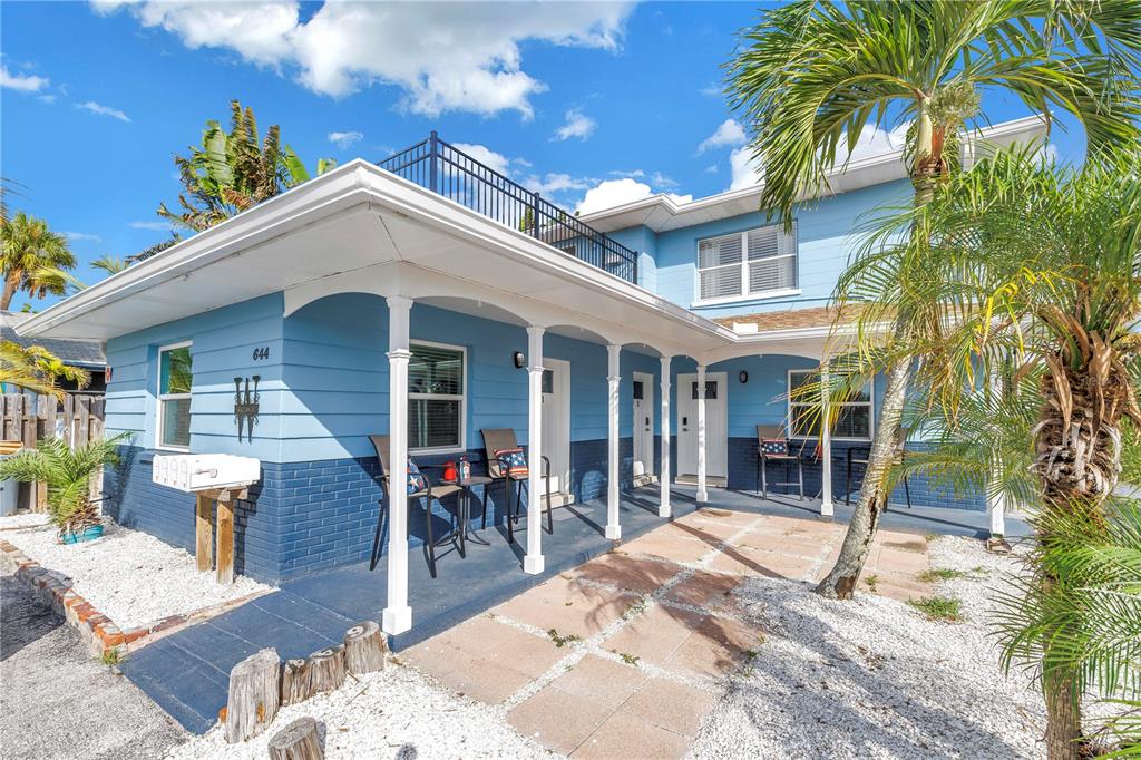 A two-story blue house with a covered porch, white columns, and a rooftop deck — 644 72ND AVENUE, ST PETE BEACH, FL