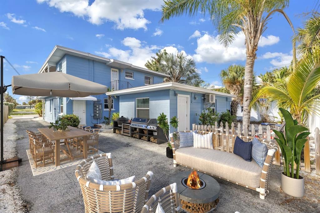 An outdoor patio area features a dining set, a fire pit, and a grill station — 644 72ND AVENUE, ST PETE BEACH, FL