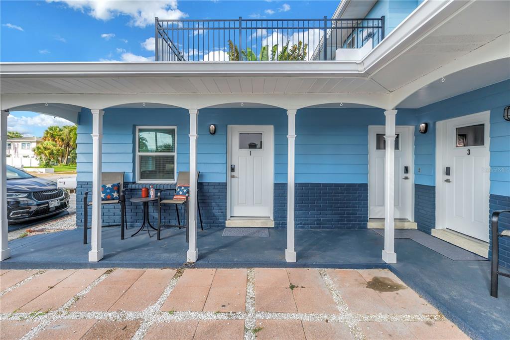 A blue building exterior features a covered porch with white columns and three numbered doors — 644 72ND AVENUE, ST PETE BEACH, FL