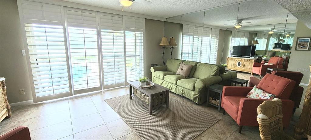 A living room features a green sofa, orange armchairs, a coffee table, and mirrored walls — 815 OCEAN SHORE BOULEVARD UNIT 7A, ORMOND BEACH, FL