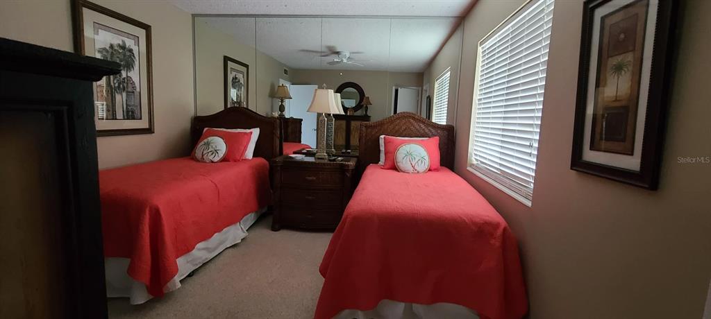 A bedroom features two twin beds with coral bedding and a shared nightstand with lamps — 815 OCEAN SHORE BOULEVARD UNIT 7A, ORMOND BEACH, FL