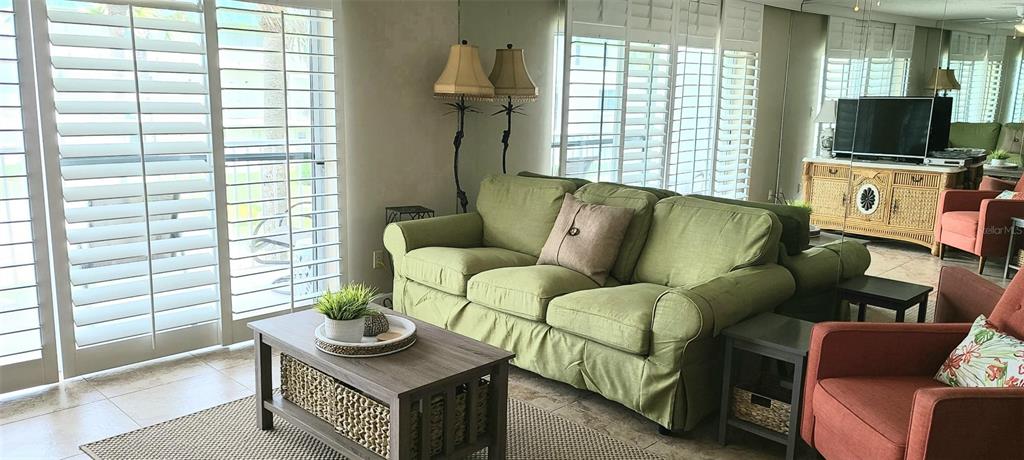 A living room features a green sofa, a wooden coffee table, and a television console — 815 OCEAN SHORE BOULEVARD UNIT 7A, ORMOND BEACH, FL