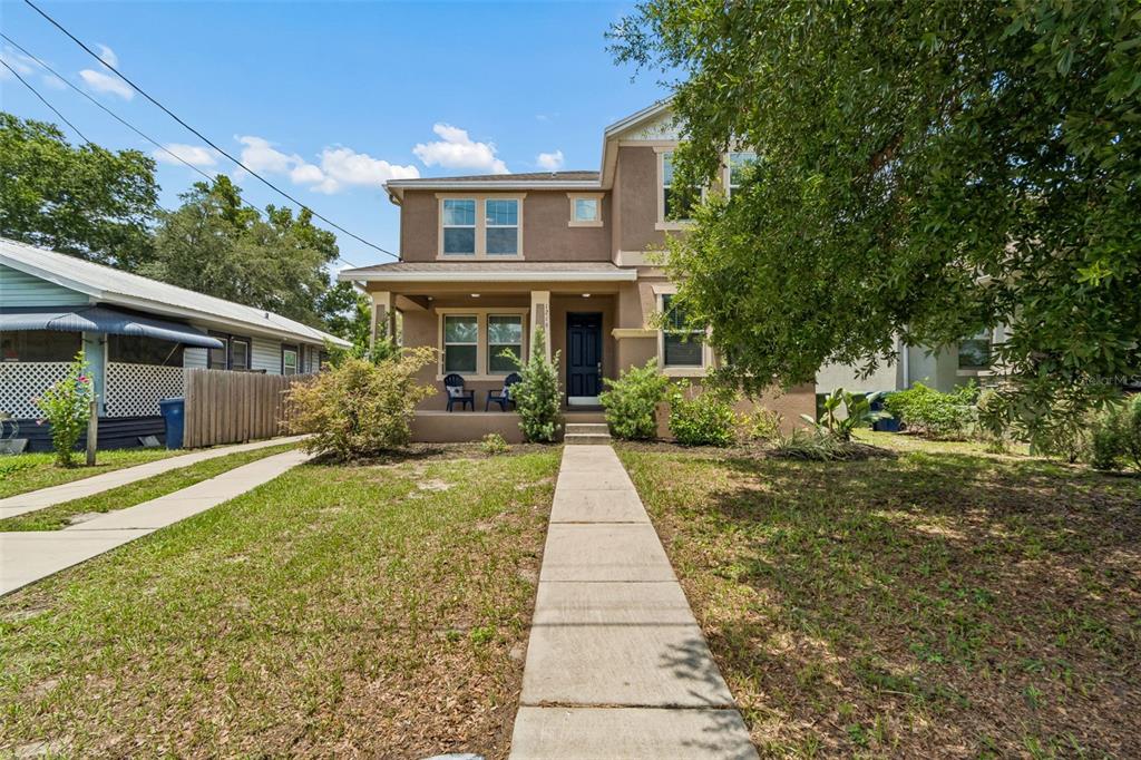 A two-story house with a front porch, tan stucco exterior, and a concrete walkway — 1216 E GIDDENS AVE, TAMPA, FL