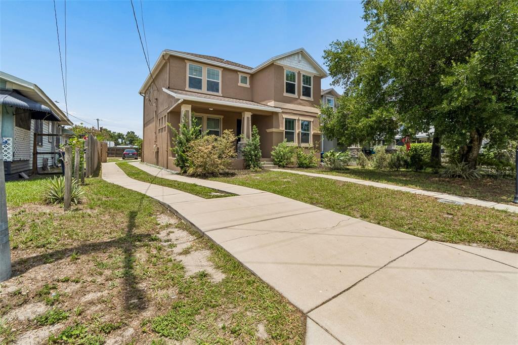 A two-story tan house with a concrete driveway and a front porch — 1216 E GIDDENS AVE, TAMPA, FL