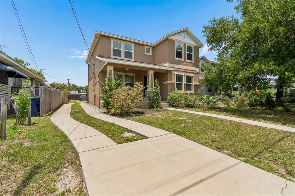 A two-story tan house with a concrete driveway and a front porch — 1216 E GIDDENS AVE, TAMPA, FL