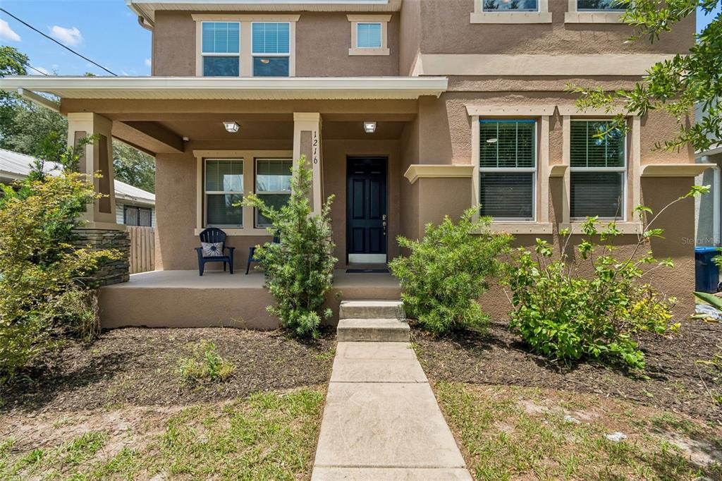 A two-story house with a tan stucco exterior, a front porch, and a concrete walkway — 1216 E GIDDENS AVE, TAMPA, FL