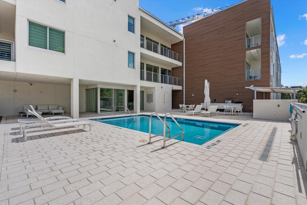 A rectangular swimming pool sits on a paved patio between two modern apartment buildings — 332 COCOANUT AVENUE UNIT 302, SARASOTA, FL