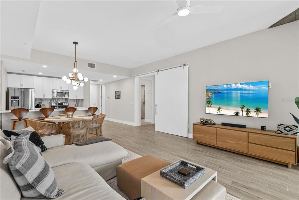 A living room with a sectional sofa, wooden media console, and an open-concept kitchen — 332 COCOANUT AVENUE UNIT 302, SARASOTA, FL