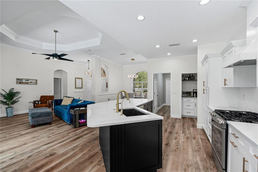 A kitchen with a dark island and white cabinets opens into a living room area — 15410 21ST AVENUE E, BRADENTON, FL