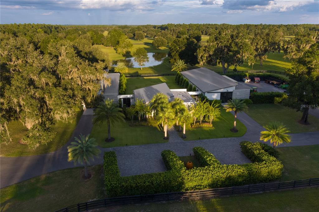 An aerial view shows a modern house with a metal roof surrounded by lush landscaping — 2875 NW 150 AVENUE, OCALA, FL