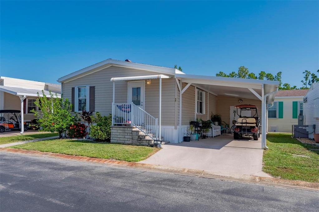 A single-story mobile home with a carport and front steps at sunset — 1000 KINGS HIGHWAY UNIT 54, PORT CHARLOTTE, FL