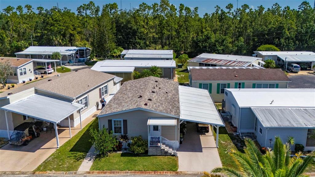 A kitchen with wood cabinets, white appliances, and a view into the adjacent living room — 1000 KINGS HIGHWAY UNIT 54, PORT CHARLOTTE, FL