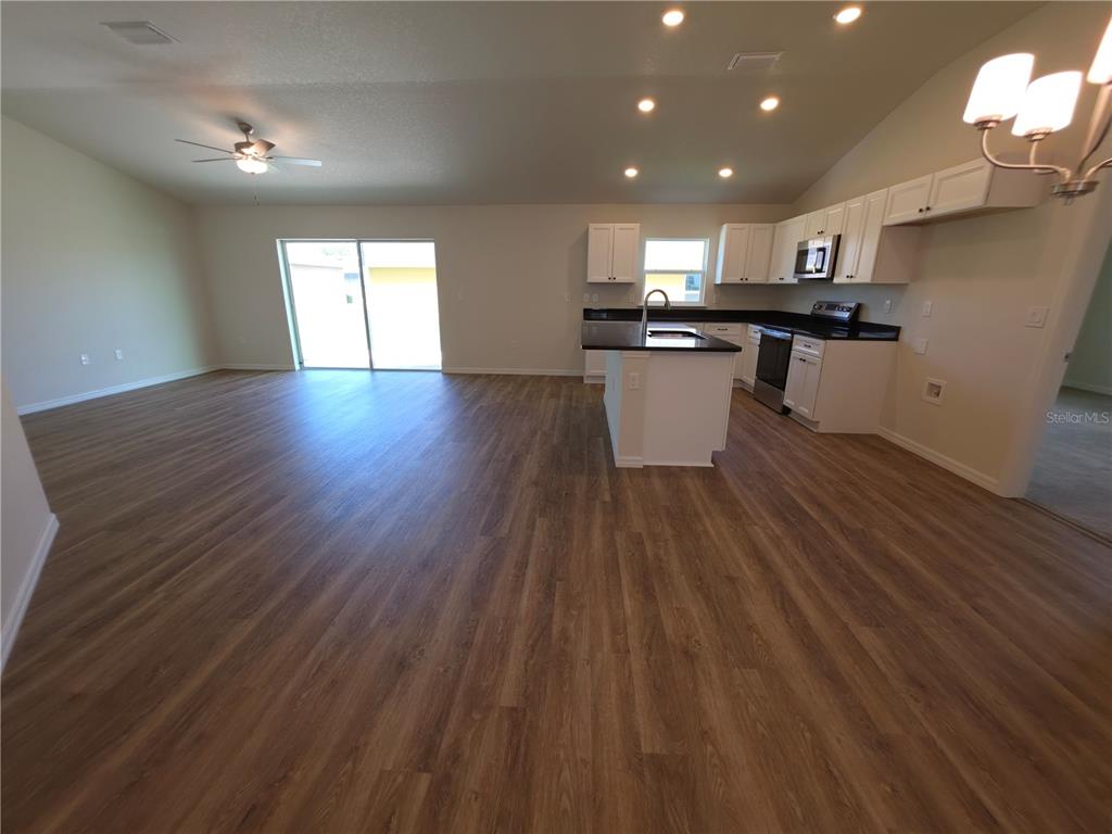 An open-concept kitchen and living area features wood-look flooring, white cabinets, and dark countertops — 8270 N WAKEFIELD DRIVE, CITRUS SPRINGS, FL