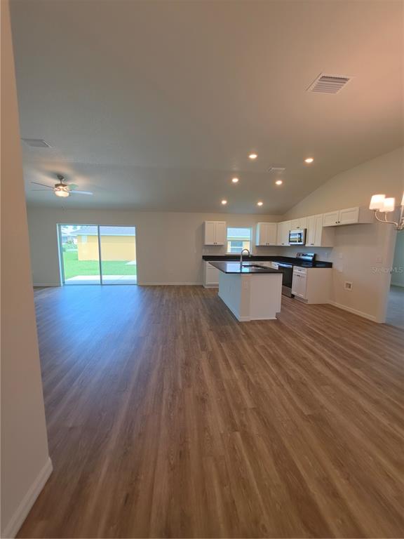 An open-concept kitchen and living area features white cabinets, dark countertops, and wood-look flooring — 8270 N WAKEFIELD DRIVE, CITRUS SPRINGS, FL