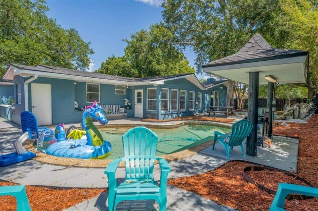 A backyard features a swimming pool with a dragon float, a patio, and a covered area — 2917 STETSON STREET, MELBOURNE, FL