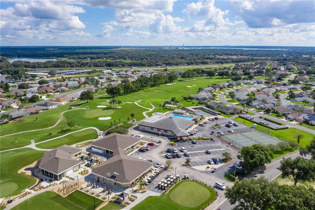 An aerial view shows a community clubhouse with a pool, tennis courts, and golf course — 5976 CORMORANT COURT, LAKELAND, FL