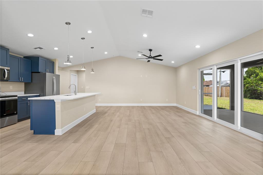 An open-concept kitchen and living area features blue cabinets, a white island, and wood flooring — 9417 HEARTWELLVILLE AVENUE, ENGLEWOOD, FL